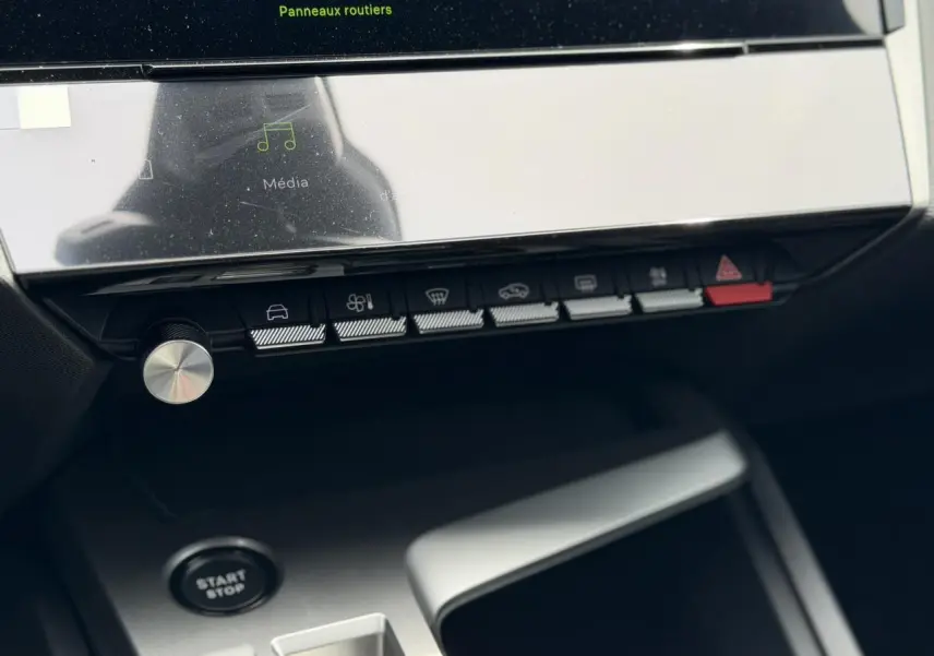 Vue rapprochée de la console centrale de la Peugeot 308 Hybrid 2026, avec écran tactile et boutons de commande noirs.