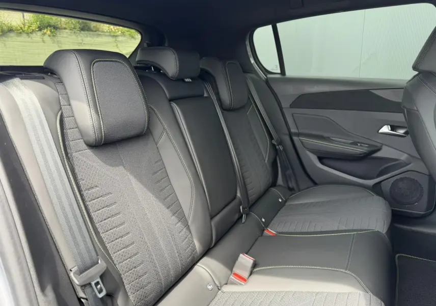 Vue latérale intérieure des sièges arrière en tissu noir avec surpiqûres vertes de la Peugeot 308 NV Hybrid 145 GT e-DSC6.
