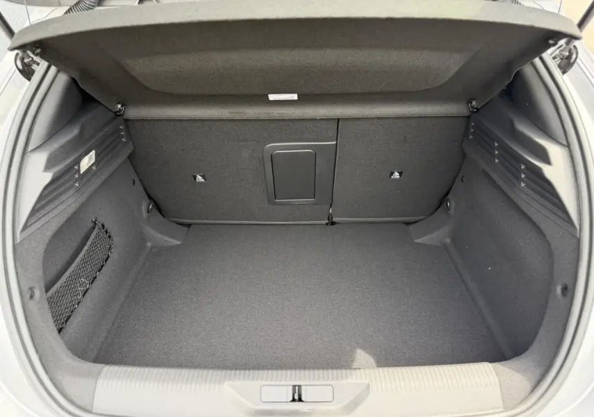 Coffre ouvert vu de l'arrière d'une Peugeot 308 gris Artense, intérieur spacieux et revêtement noir.