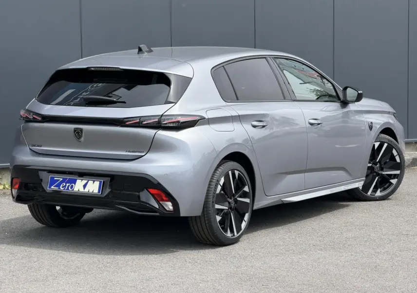 Peugeot 308 NV Hybrid gris Artense vue 3/4 arrière droit, jantes bi-tons et feux arrière LED 3 griffes.