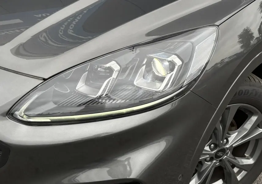 Gros plan sur le phare avant droit et la roue alliage 18 pouces gris graphite du Ford Kuga 2023 finition ST-Line.