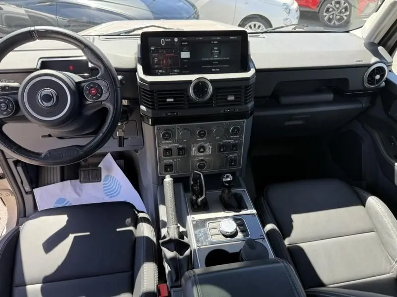 Vue intérieure de l'INEOS Grenadier 2024 beige, montrant le tableau de bord moderne et la console centrale avec commandes multiples.