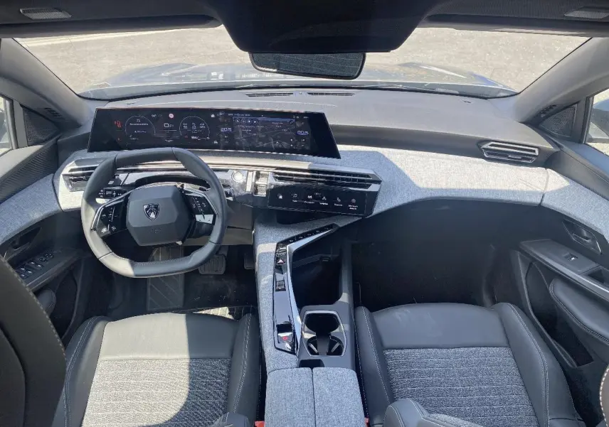 Vue intérieure avant du Peugeot 5008 Hybrid 145 allure e-dcs6 2025, avec tableau de bord numérique et sellerie gris clair.