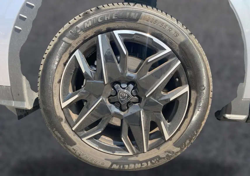 Gros plan sur la roue avant droite gris artense d’un Peugeot 5008 Hybrid 145 allure e-dcs6 avec jante alu noire et argent.
