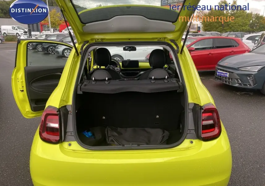 Vue arrière ouverte de la FIAT 500 électrique 2024 en jaune acid, coffre et porte côté gauche ouverts, intérieur visible.