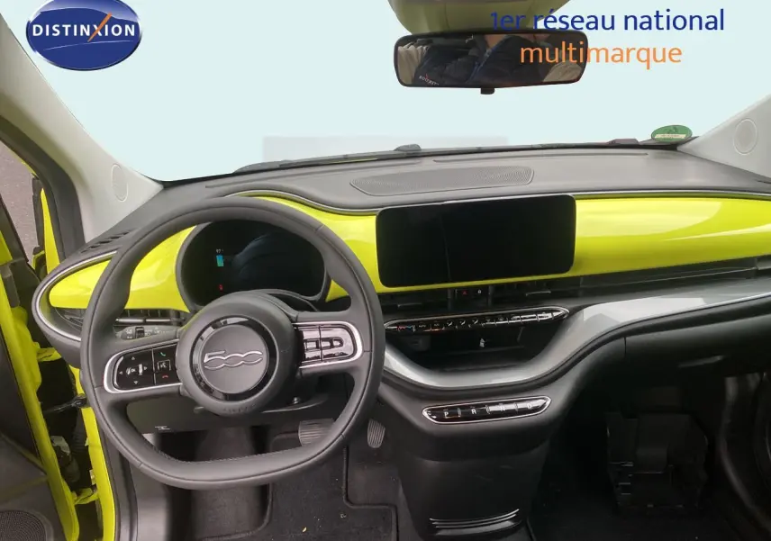Vue intérieure avant du tableau de bord jaune acid de la Fiat 500 électrique 2024 avec volant multifonction et écran tactile.