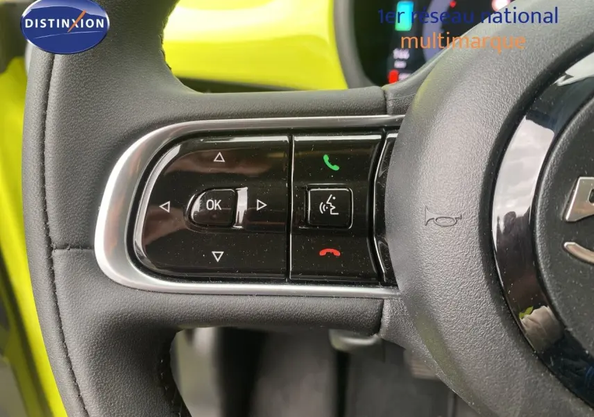 Gros plan sur les commandes gauche du volant d’une FIAT 500 électrique jaune acid 2024, avec boutons multifonctions.