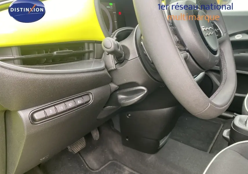 Vue intérieure côté conducteur de la FIAT 500 électrique 2024 avec tableau de bord jaune acid et volant cuir noir.