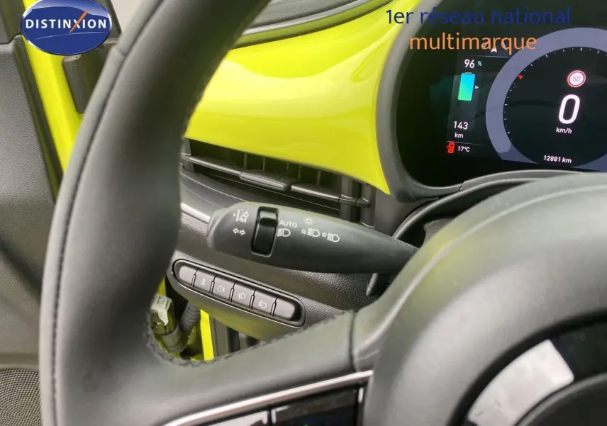 Vue intérieure centrée sur le volant et tableau de bord jaune acidulé de la FIAT 500 électrique 2024.