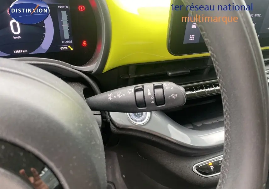 Vue intérieure rapprochée du volant et du tableau de bord jaune acidulé de la FIAT 500 électrique 2024.