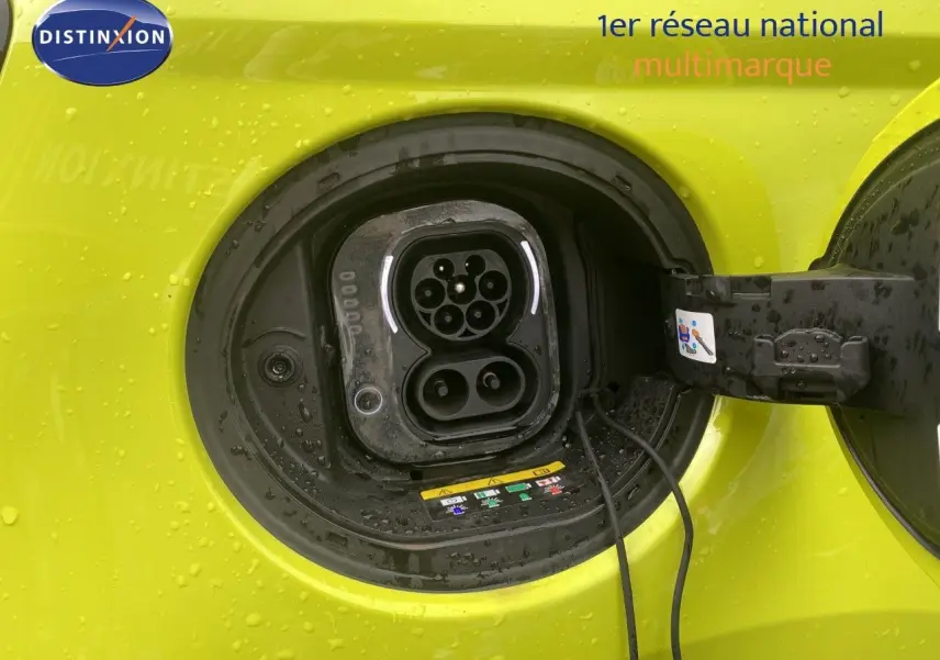 Prise de recharge électrique ouverte sur la côté gauche d'une FIAT 500 jaune acid 2024, avec gouttes d'eau visibles.