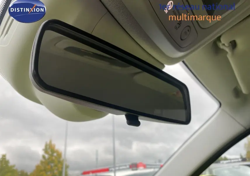 Rétroviseur intérieur de la FIAT 500 électrique 2024, vue rapprochée sous plafond clair avec ciel nuageux en arrière-plan.