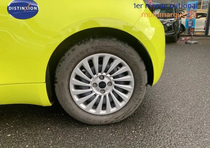 Gros plan sur la roue arrière droite d'une FIAT 500 électrique 2024 en jaune acid avec jante argentée multibranches.