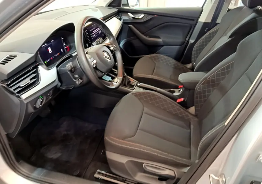 Intérieur avant droit du Skoda Kamiq gris clair 2022, sièges noirs avec surpiqûres et tableau de bord digital.