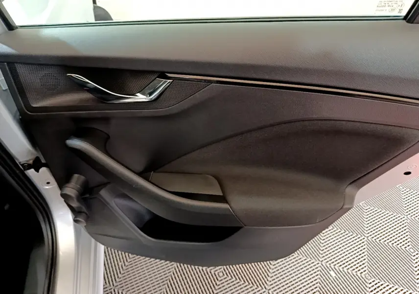 Gros plan sur la porte arrière gauche gris clair du Skoda Kamiq 2022, avec poignée chromée et panneau noir texturé.