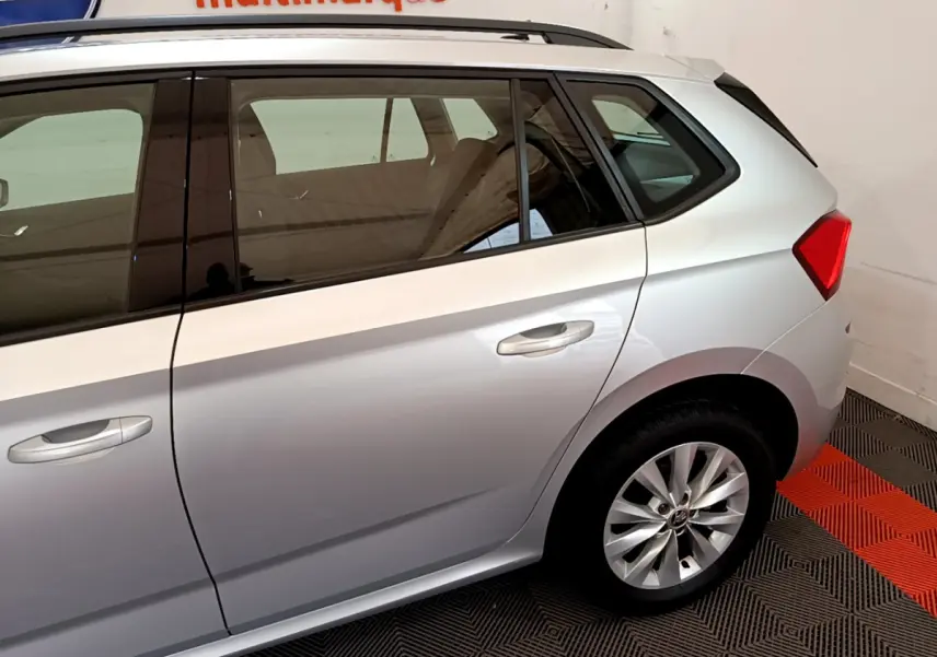 Vue latérale côté droit du Skoda Kamiq gris clair 2022, mettant en valeur la porte arrière et la roue arrière.