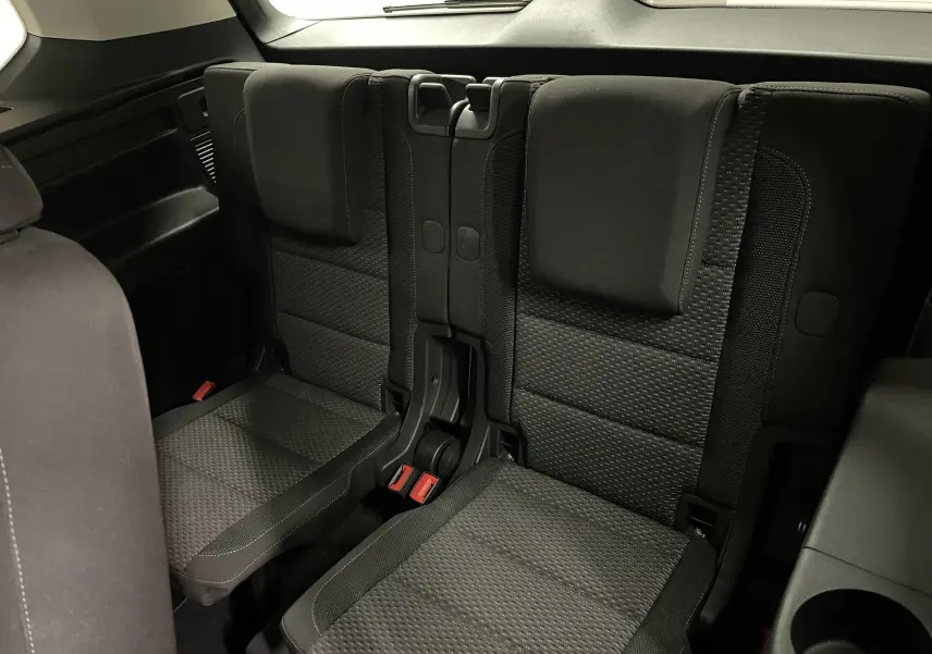 Vue rapprochée des sièges arrière en tissu noir du Volkswagen Touran 2024, version 7 places, sans appuie-tête central.
