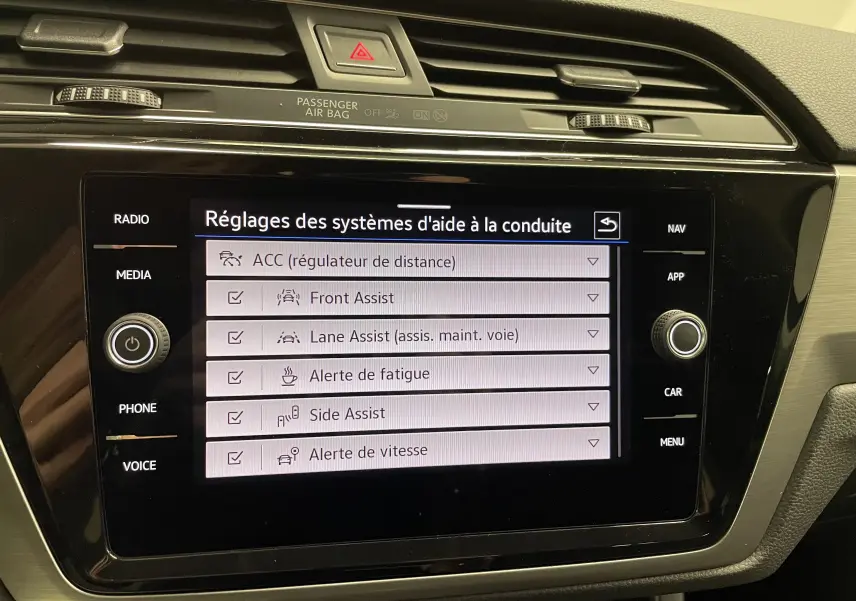 Écran tactile central du Volkswagen Touran 2024 affichant les réglages des aides à la conduite, intérieur noir et beige.