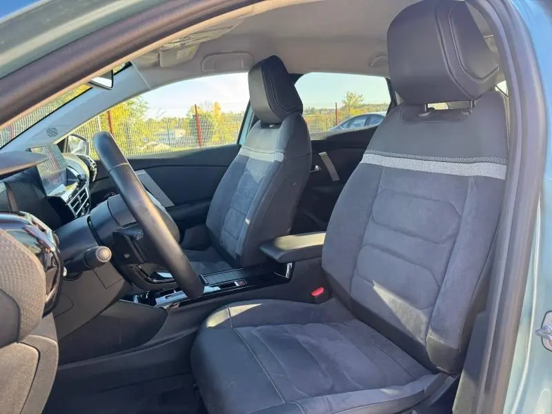 Vue intérieure côté conducteur du Citroën C4 2024 gris, montrant les sièges avant et le volant.