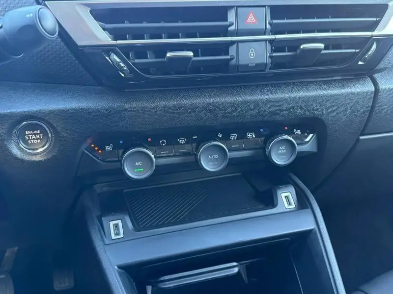 Vue rapprochée du tableau de bord de la Citroën C4 2024 gris, montrant les commandes de climatisation et le bouton start/stop.
