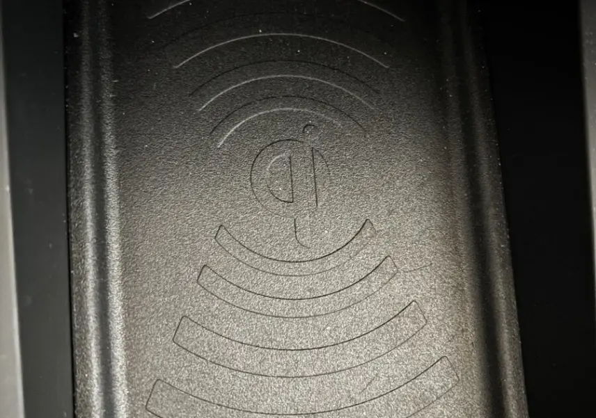 Gros plan sur la zone de recharge par induction noire du DS3 2024, avec symbole Qi gravé au centre.