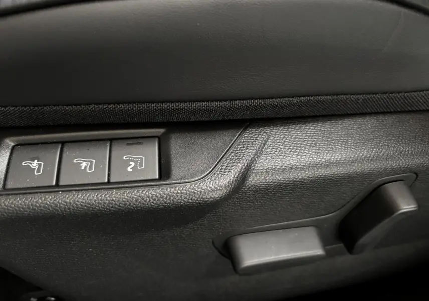 Gros plan sur les commandes de réglage des sièges côté conducteur d’une DS3 noire, intérieur en plastique texturé noir.