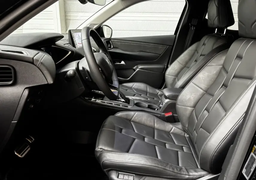 Vue intérieure côté conducteur de la DS3 2024, sièges en cuir noir avec console centrale et écran tactile visible.