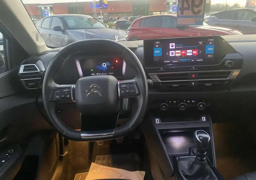 Vue intérieure du poste de conduite de la Citroën C4 blanche 2021, volant multifonction et écran tactile central visible.
