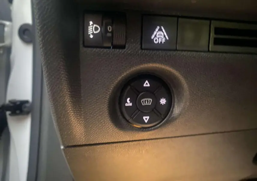 Détail du tableau de bord côté gauche d’une Citroën C4 blanche 2021, montrant les commandes d’éclairage et d’aide à la conduite.