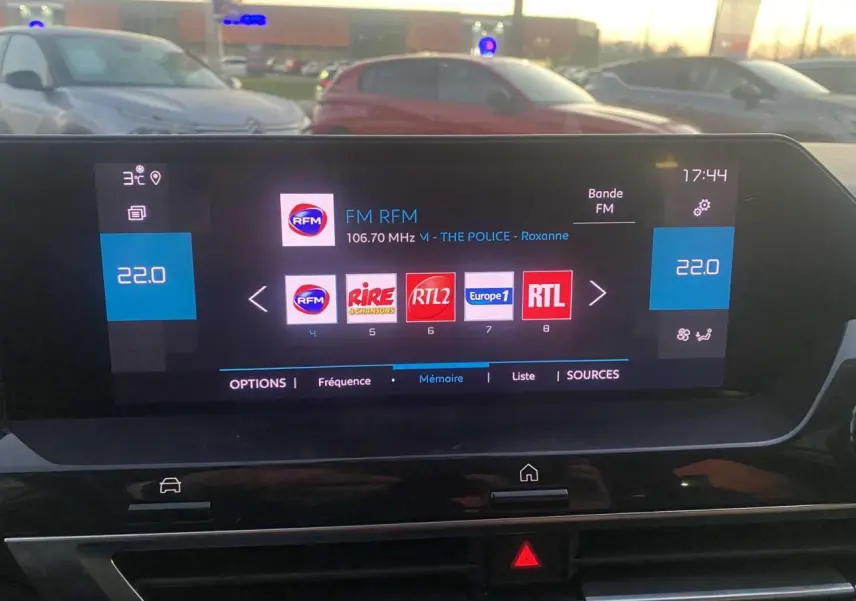 Écran tactile central de la Citroën C4 blanche 2021 affichant les stations radio FM en soirée.
