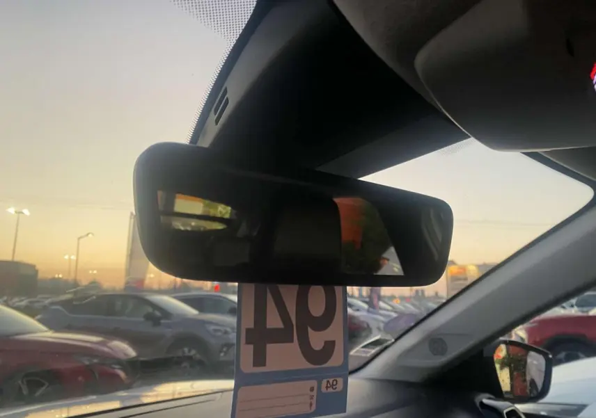 Vue intérieure du rétroviseur central d'une Citroën C4 blanche 2021, avec vue sur un parking au crépuscule.