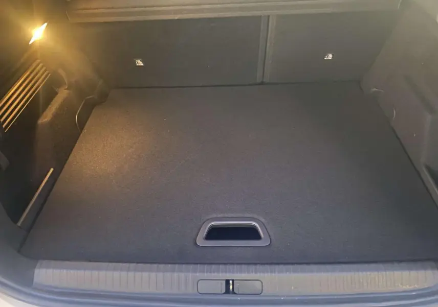 Coffre ouvert de Citroën C4 blanc 2021, vue intérieure montrant le plancher plat et l'éclairage latéral.
