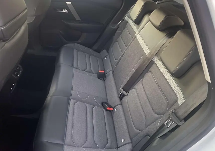 Vue intérieure montrant la banquette arrière grise et noire du Citroën C4 blanc, avec ceintures de sécurité et appuie-têtes.
