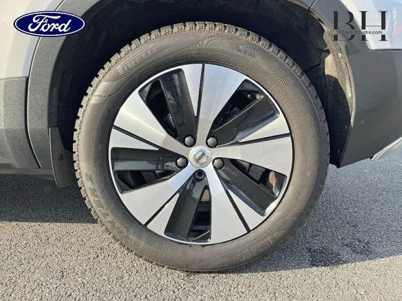 Gros plan sur la roue avant droite d’un Volvo XC40 gris Glacier avec jante alu bicolore noir et argent.