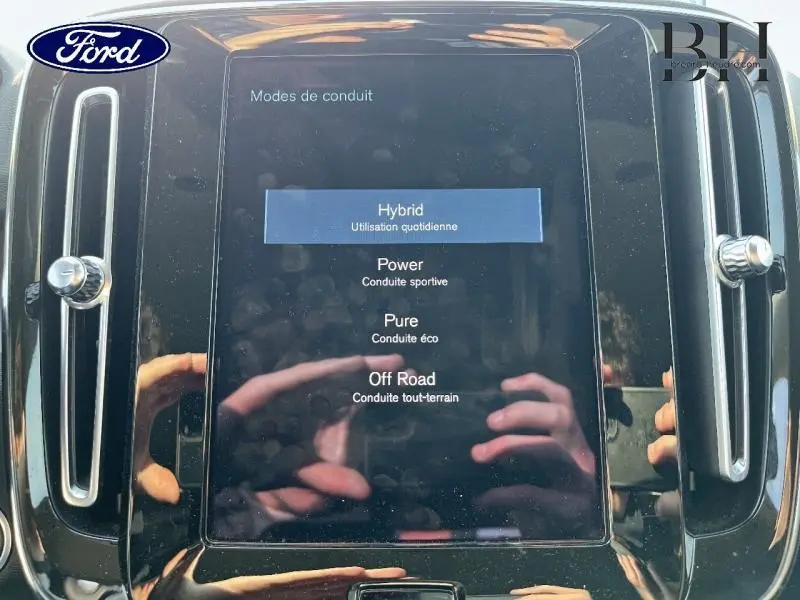 Écran tactile central du Volvo XC40 T5 Recharge affichant les modes de conduite, entouré de finitions noires brillantes.