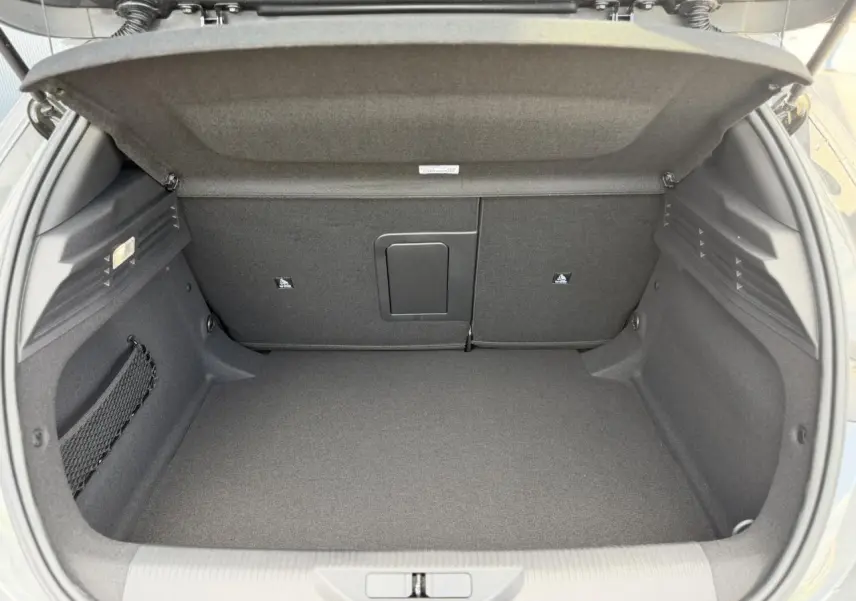 Coffre ouvert vu de l'arrière d'une Peugeot 308 gris Selenium, avec banquette rabattable et filet de rangement latéral.