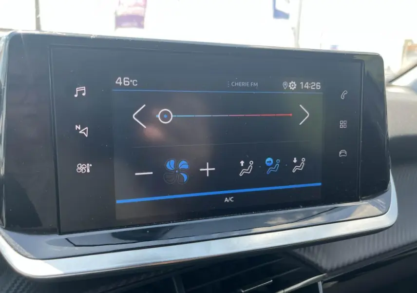 Écran tactile central de la Peugeot 208 2023 en gris clair, affichant les réglages de climatisation et la température extérieure.