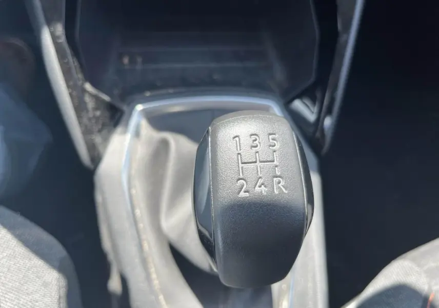 Gros plan sur le levier de vitesses manuel noir de la Peugeot 208 gris clair 2023, montrant les rapports gravés.