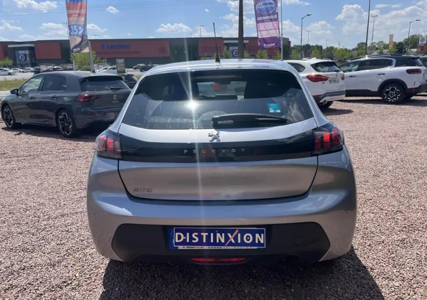 Vue arrière d'une Peugeot 208 gris clair 2023, avec logo et bande noire distinctive sur le hayon.