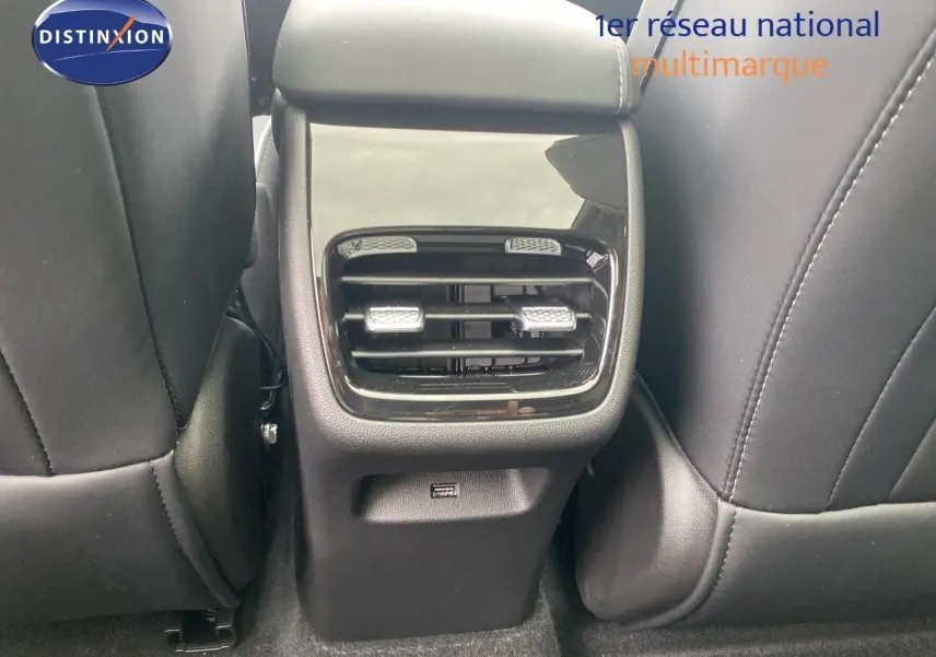 Détail de la console arrière avec sorties d’air noires et port USB, entre sièges avant en cuir noir.