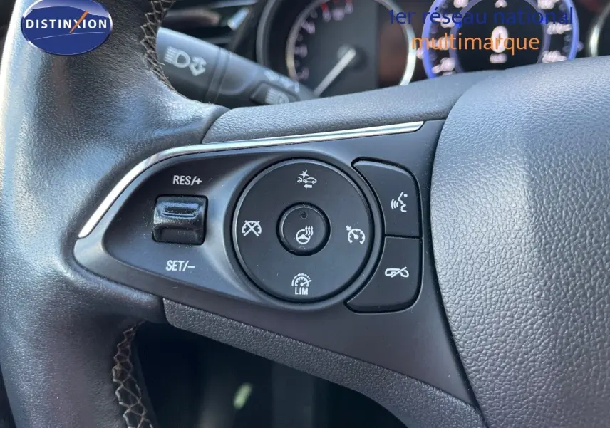 Gros plan sur les commandes au volant de l'Opel Insignia 2.0D 174CH Elegance, volant en cuir noir avec surpiqûres.