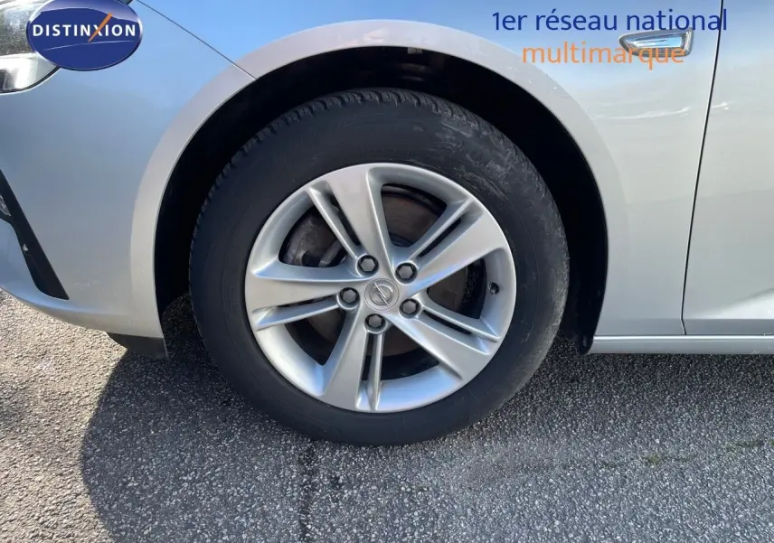 Gros plan sur la roue avant gauche d'une Opel Insignia gris minéral métal, mettant en valeur la jante alliage.