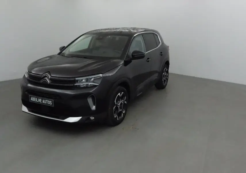 Citroën C5 Aircross noir vue 3/4 avant droit dans un intérieur neutre, avec jantes distinctives et calandre moderne.