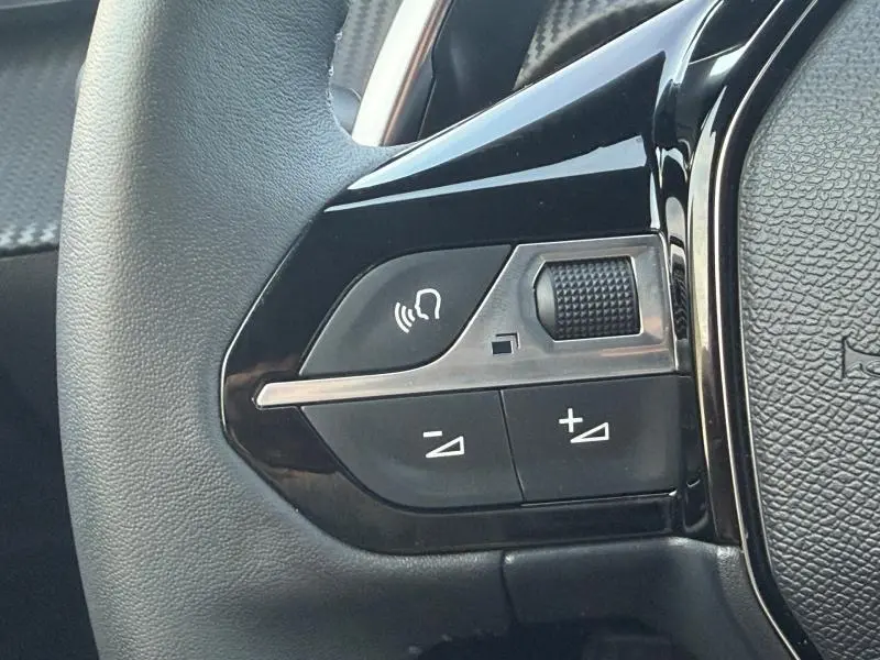 Gros plan sur les commandes gauche du volant noir du Peugeot 2008 1.2 Hybrid 136ch Allure rouge Elixir 2024.