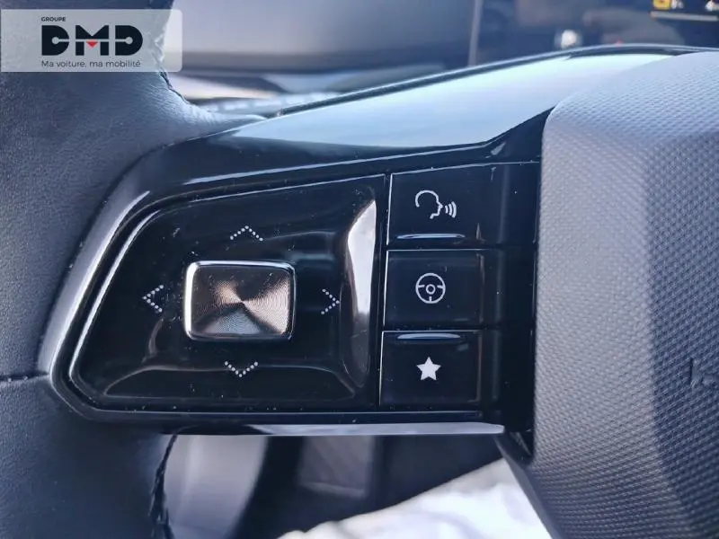 Gros plan sur les commandes noires à gauche du volant du MG4 Andes Grey, avec boutons de navigation et fonctions vocales.