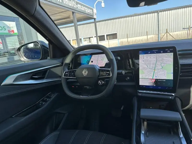 Vue intérieure côté conducteur du Renault Austral 2025 Bleu Iron, avec tableau de bord numérique et grand écran tactile central.