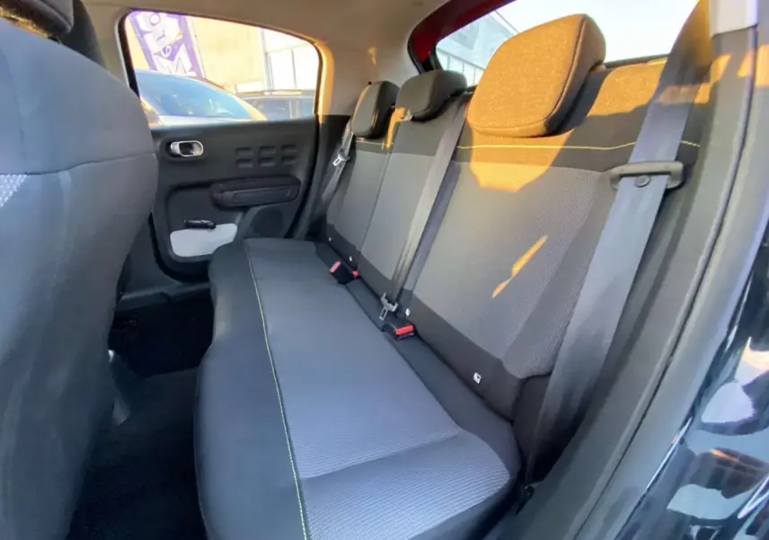 Vue intérieure côté droit montrant la banquette arrière grise avec surpiqûres jaunes de la Citroën C3 Shine 2023 toit rouge.