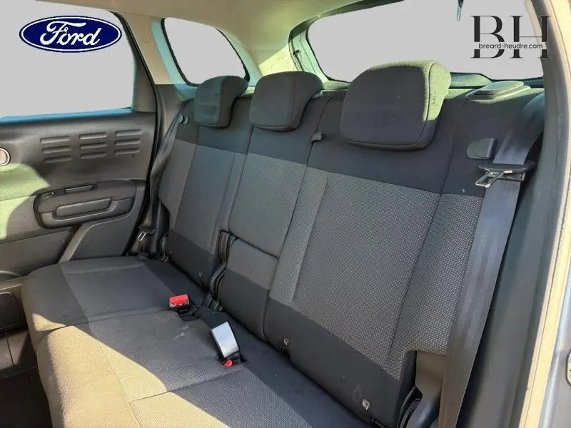 Vue intérieure de la banquette arrière en tissu gris foncé du Citroën C3 Aircross, avec appuie-têtes et ceintures visibles.