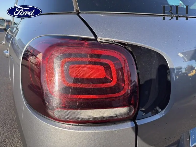 Gros plan sur le feu arrière droit d'une Citroën C3 Aircross gris acier, soulignant le design carré lumineux.