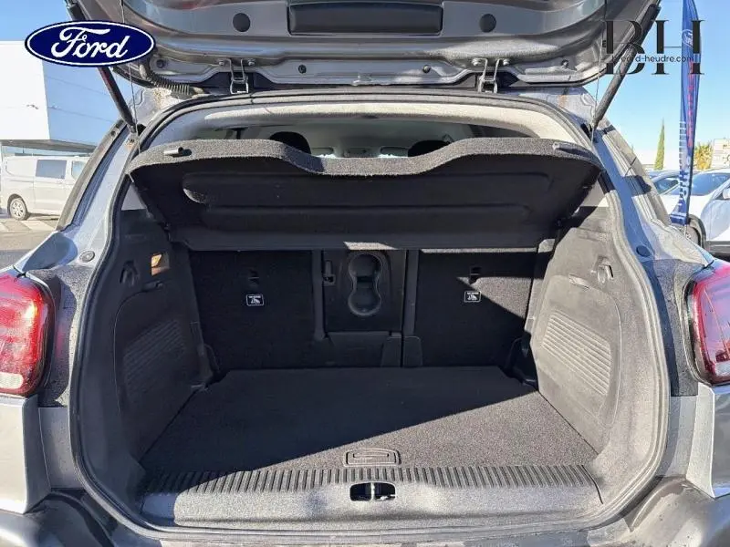 Coffre ouvert vu de l'arrière d'un Citroën C3 Aircross gris acier, montrant l'espace de chargement vide.
